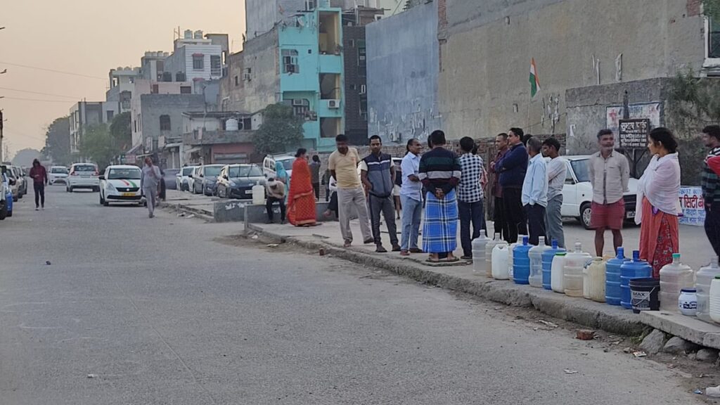 People queing in a street with empty water bottles.